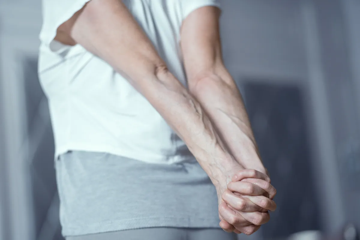 stretching hands behind back: exercise to treat shoulder drop